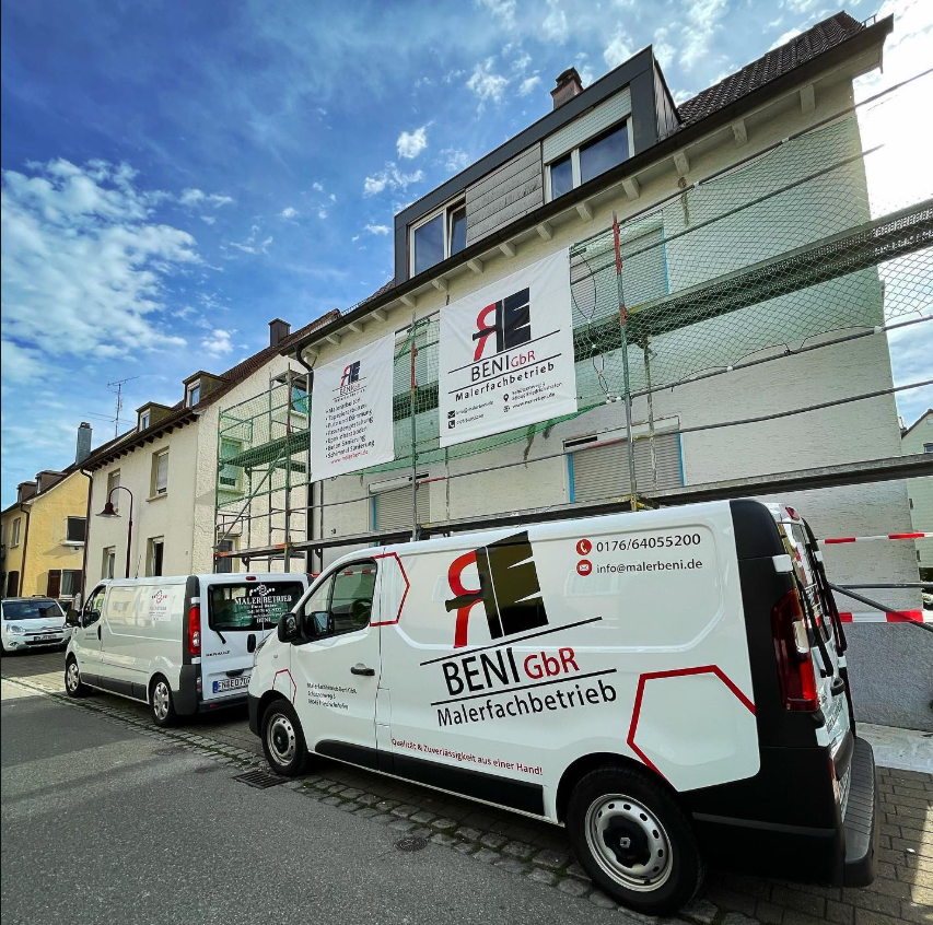 Fahrzeuge und Ger&uuml;st von Maler Beni vor einer einger&uuml;steten Fassade